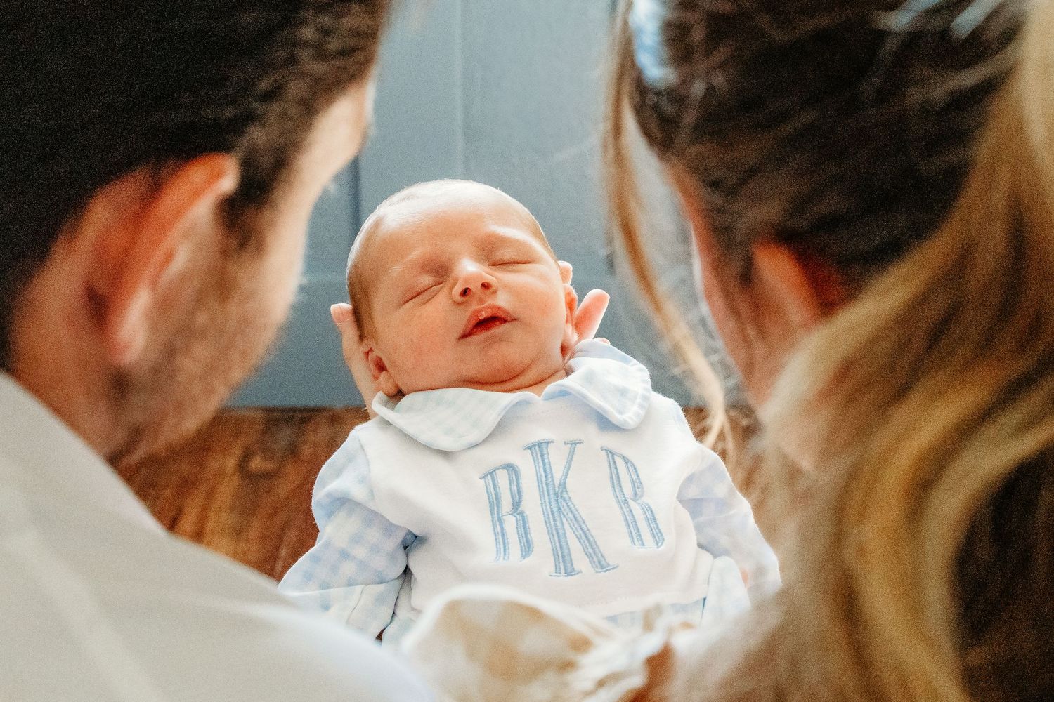 A newborn baby being gently cradled and supported in loving hands in DFW.