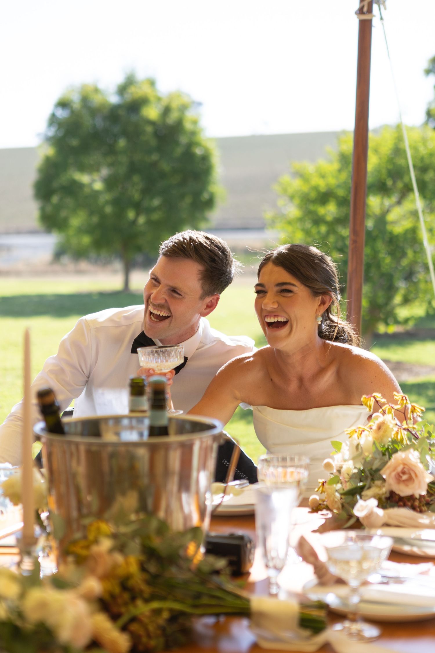 Bride and groom laughing during speeches in marquee at country wedding