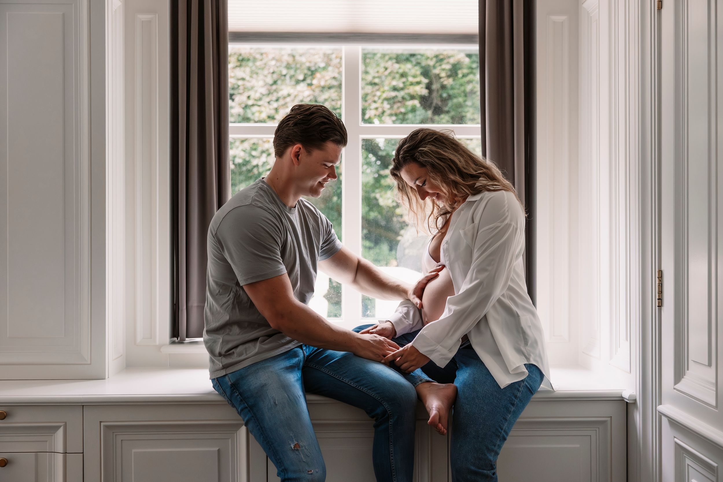 Family photoshoot in a bright indoor setting with large windows and natural light.