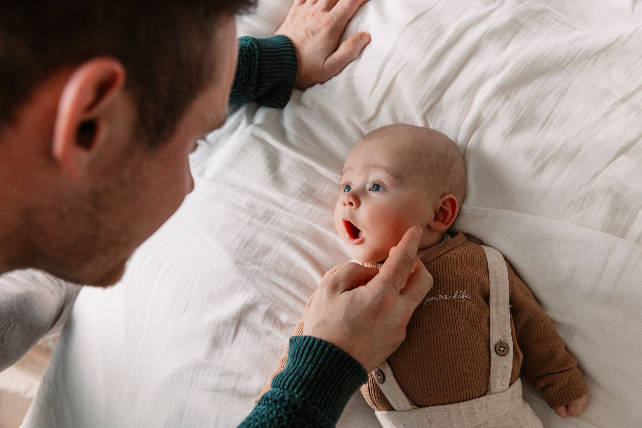 Close-up shot of a newborn baby's tiny hand being gently held against a white blanket.