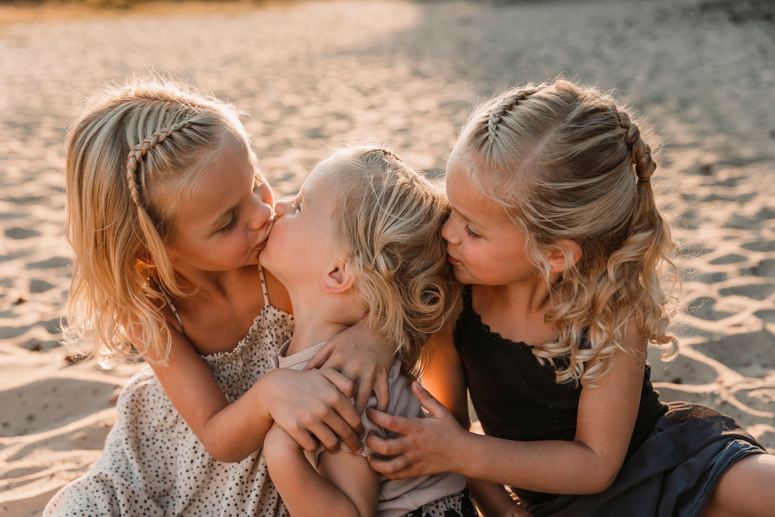 Family sharing intimate moments together on sandy beach during golden hour.