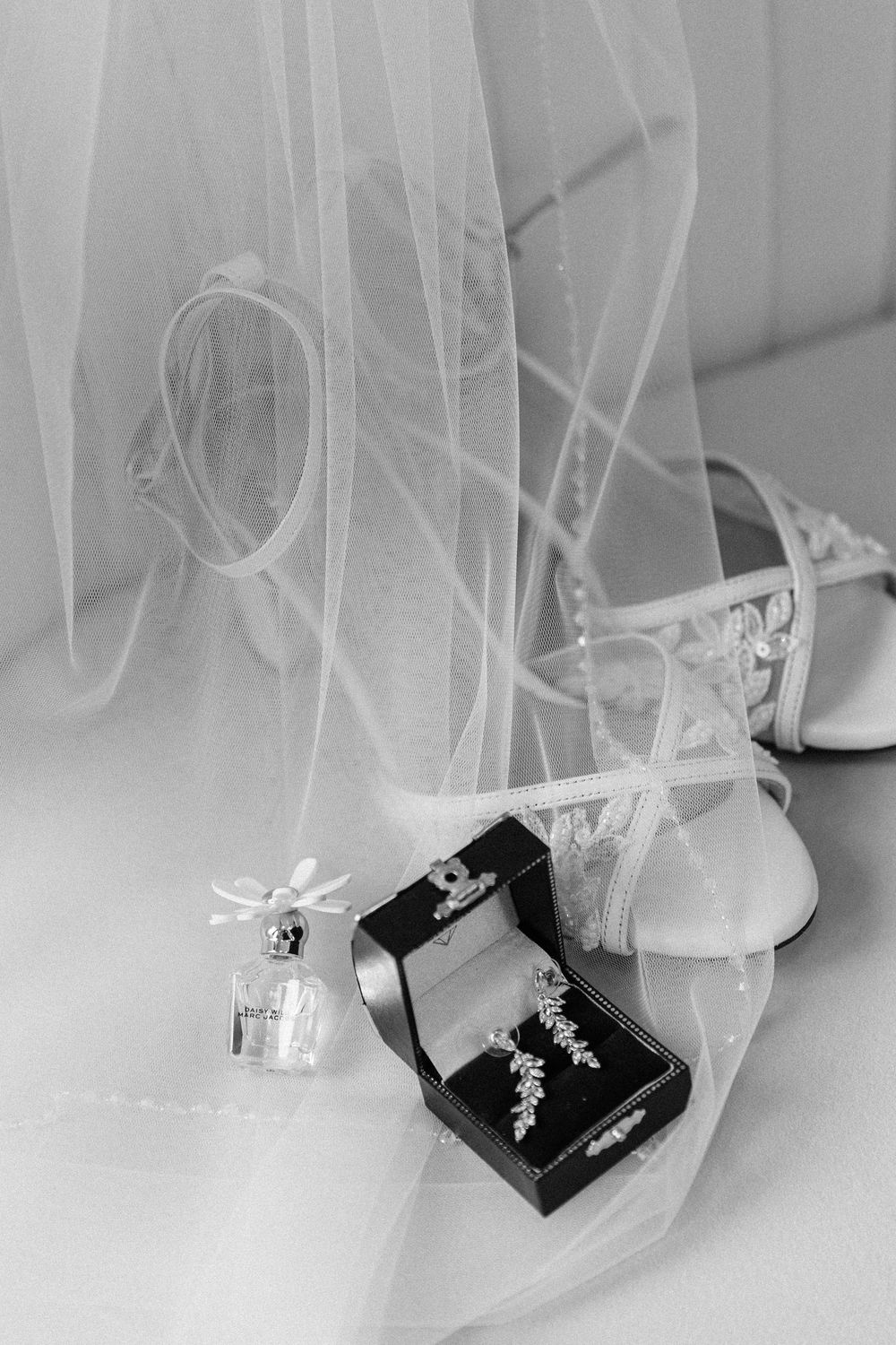 Wedding jewelry boxes and accessories displayed beneath flowing white tulle veil fabric.
