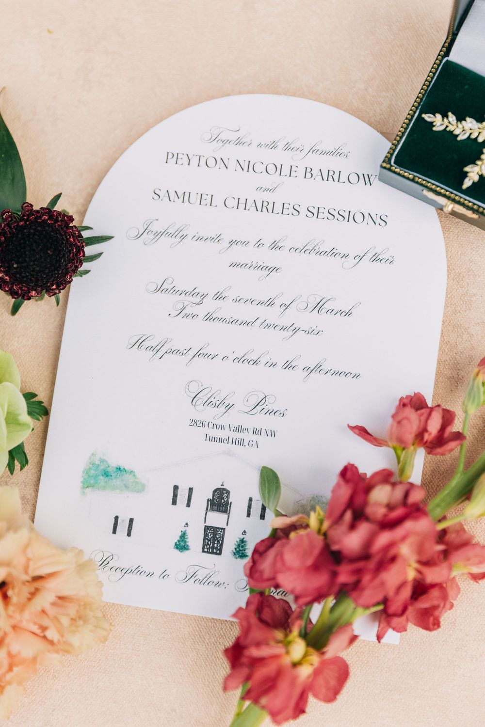 Wedding invitation details with red and peach floral accents arranged on a neutral background.