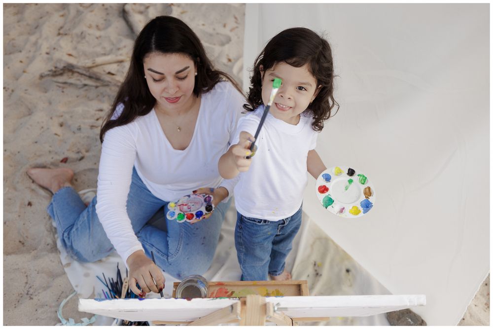 People sitting together on floor painting and creating art with colorful palettes and supplies.
