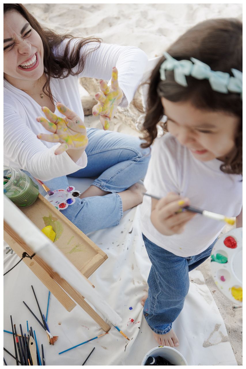 People engaged in a creative art session painting and drawing together on a white surface with colorful art supplies.
