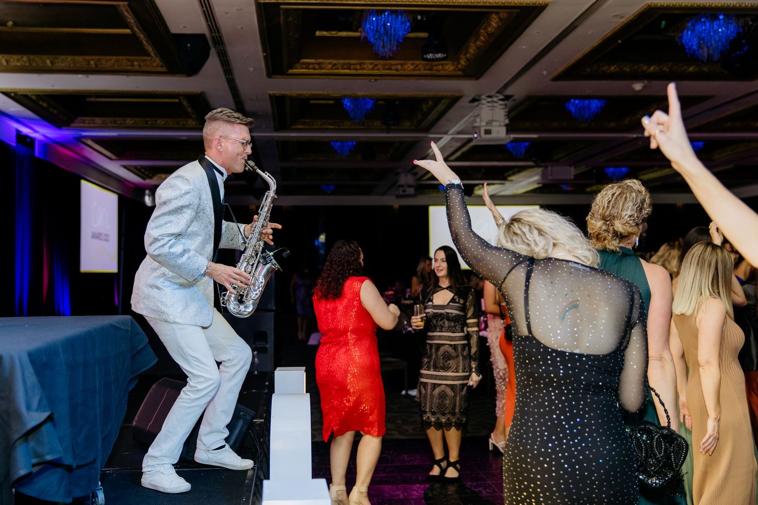 Saxophonist playing at an awards night event for guests on the dance floor