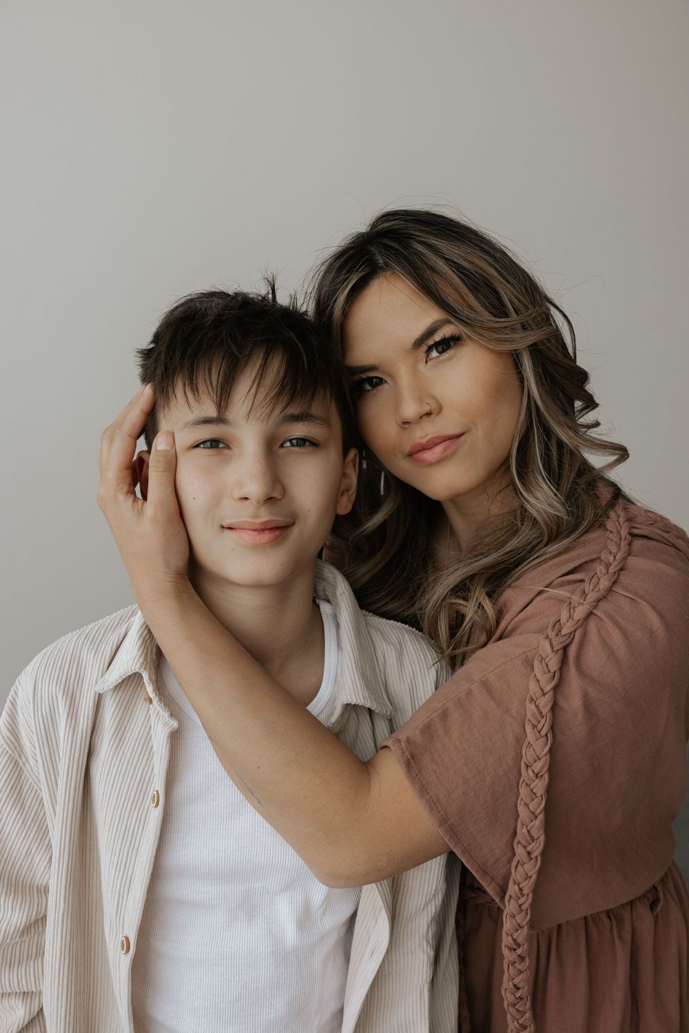 Two people in casual attire pose together against a neutral background in a series of intimate portrait shots.