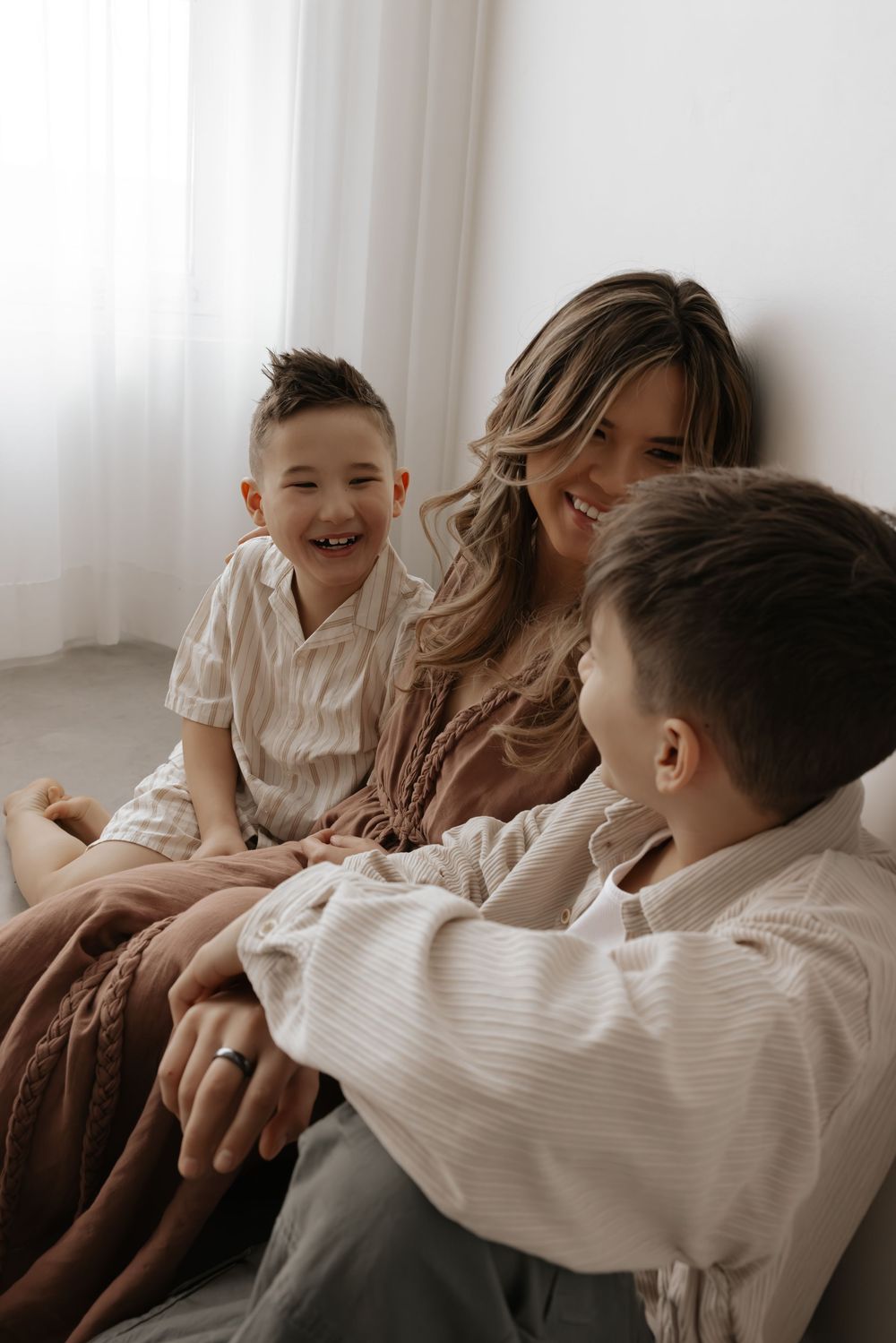 Family members share joyful laughter while relaxing together on a light colored couch.