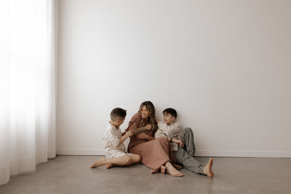 Group lounging casually in a minimalist white room with sheer curtains.