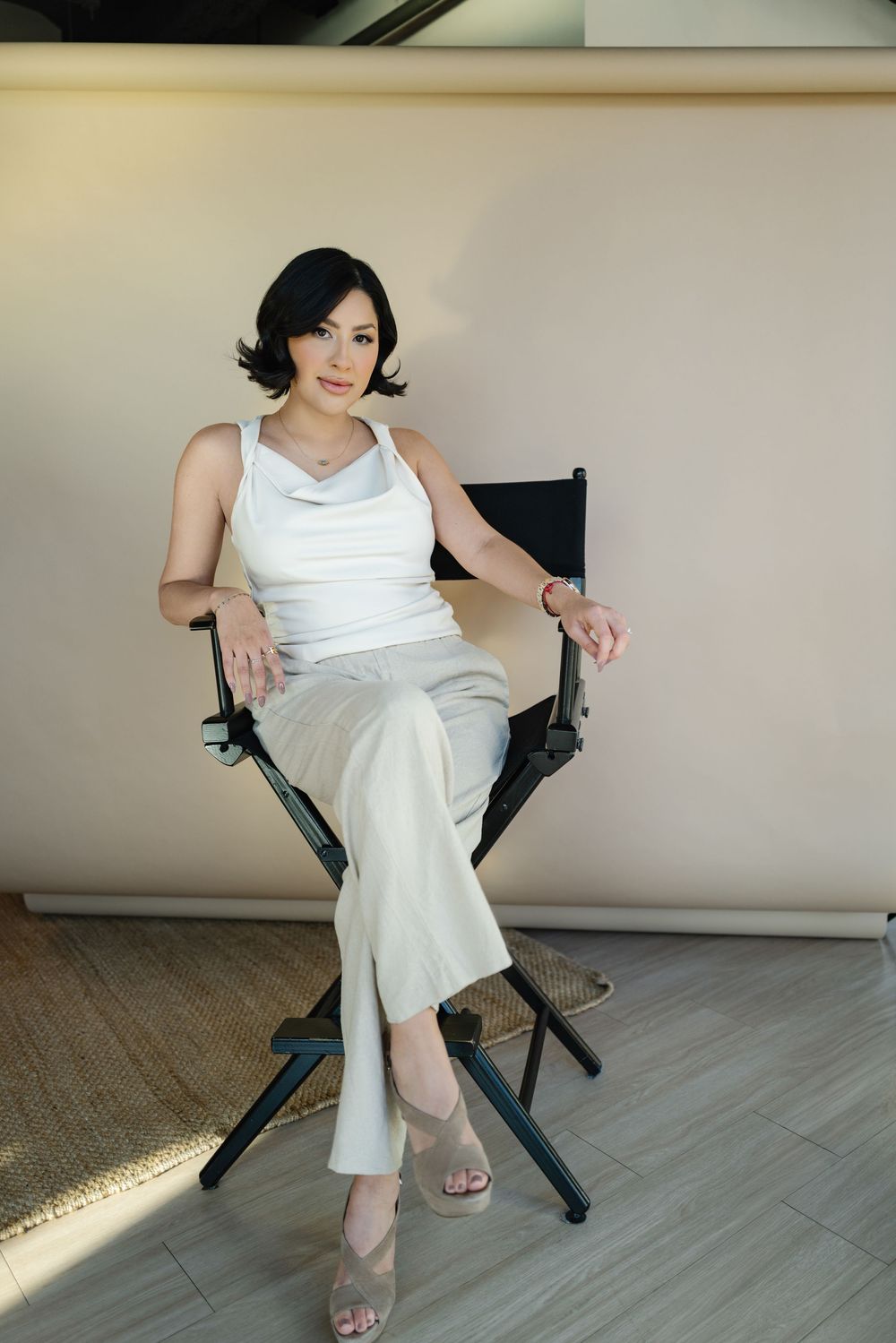 Person in a white dress sitting on a black folding chair with sunlight streaming across the floor.
