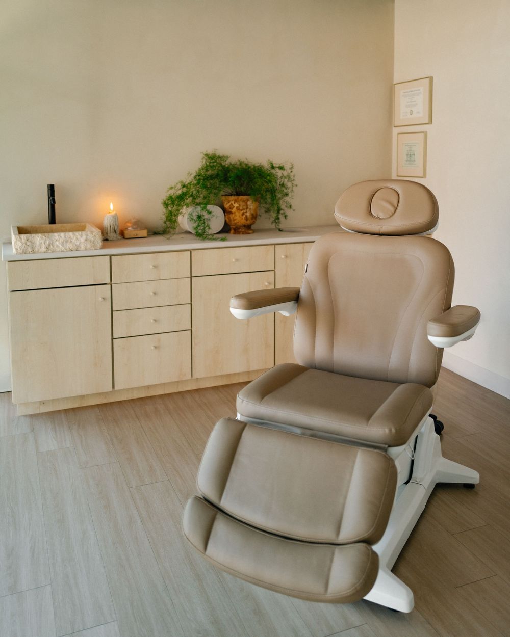 Beige leather salon chair shown from multiple angles in a minimalist spa room with light wood flooring.