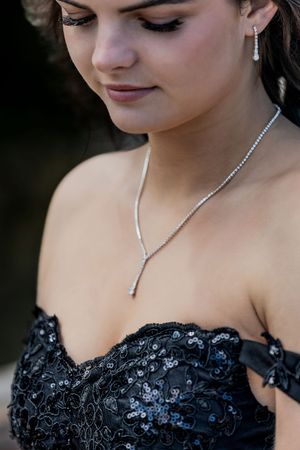 Close-up of teen in black sequin prom dress wearing elegant diamond necklace and earrings.