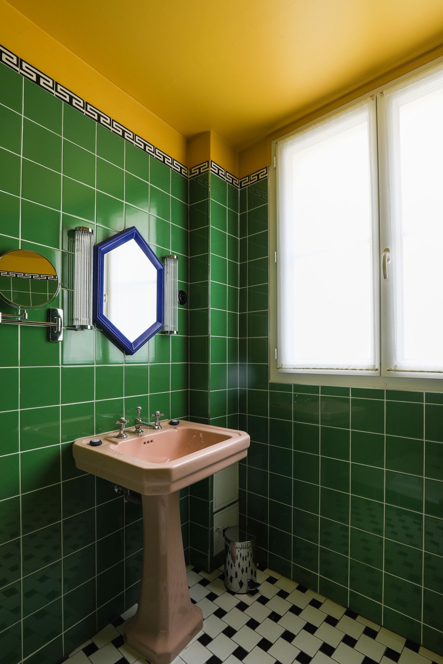 Vintage bathroom interior with emerald green tile walls, black and white checkered floor, and pink pedestal sink.