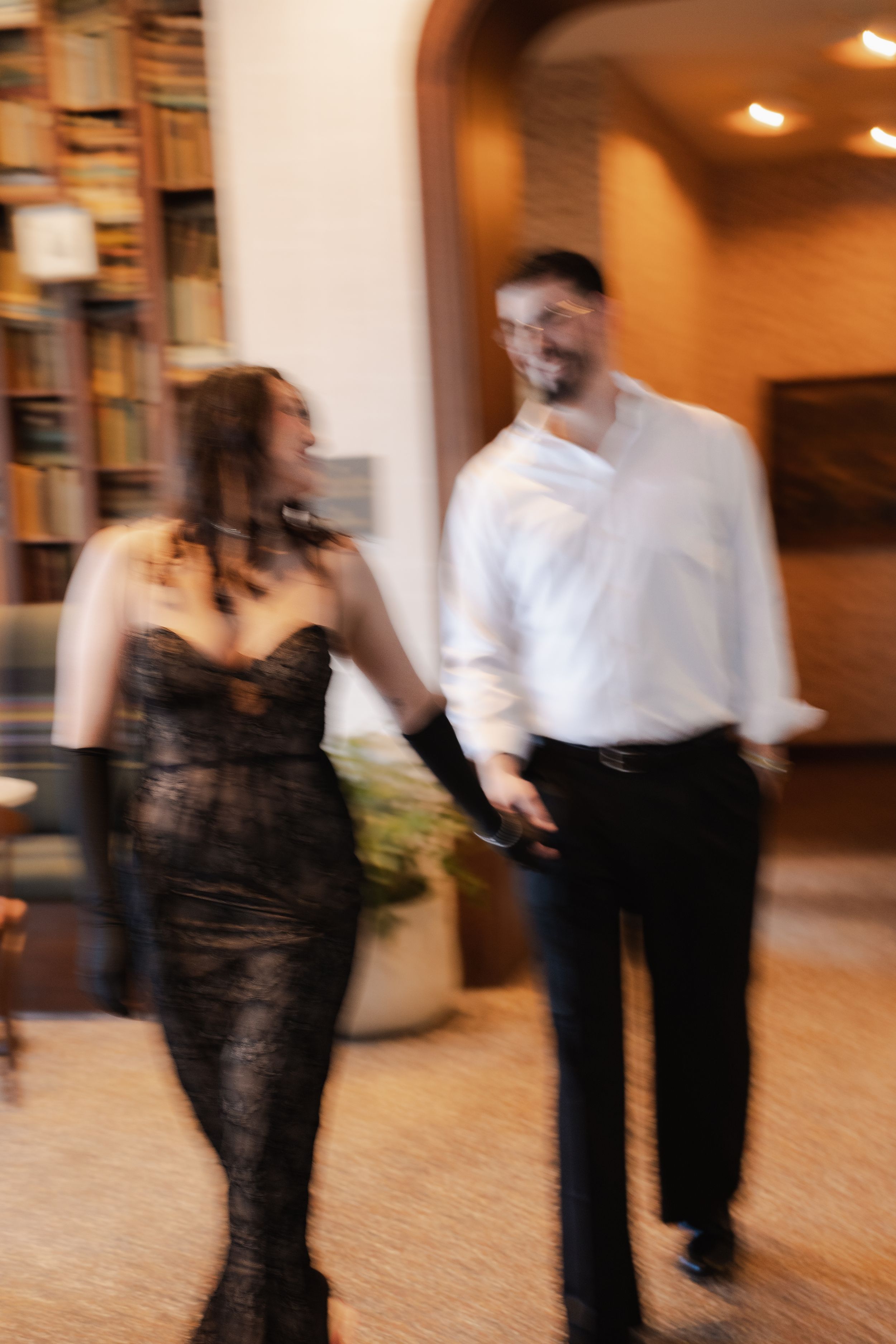 Blurred motion sequence of dancers performing ballroom dance moves on a carpeted floor in warm lighting.