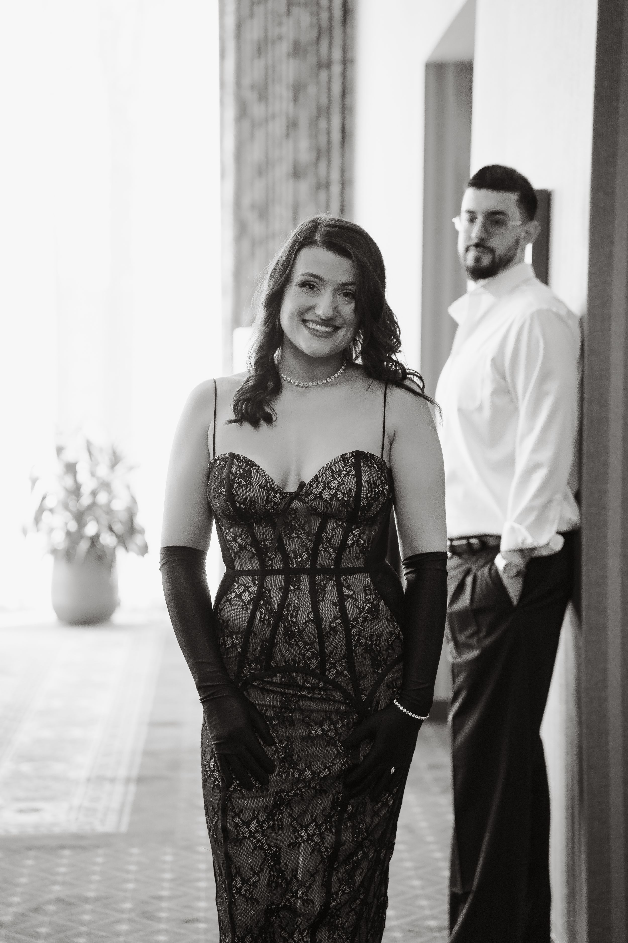 Black and white portrait of a couple in formal attire posing in an elegant indoor setting.