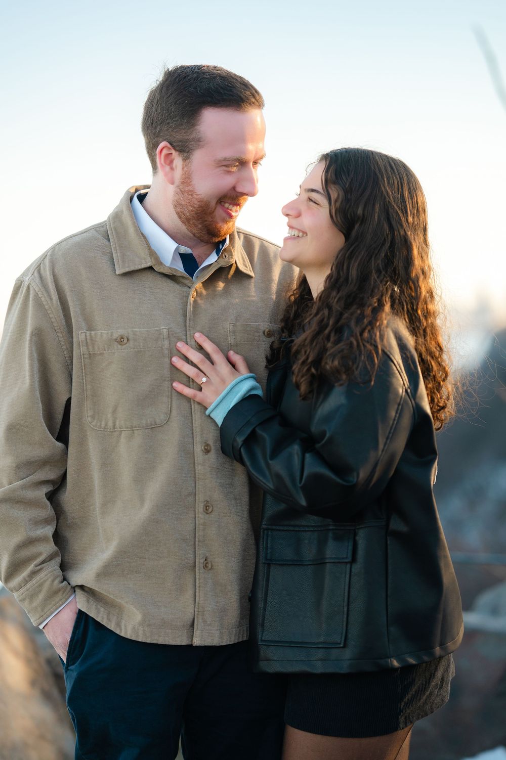 A couple in casual attire sharing intimate moments during a sunset photo session outdoors.