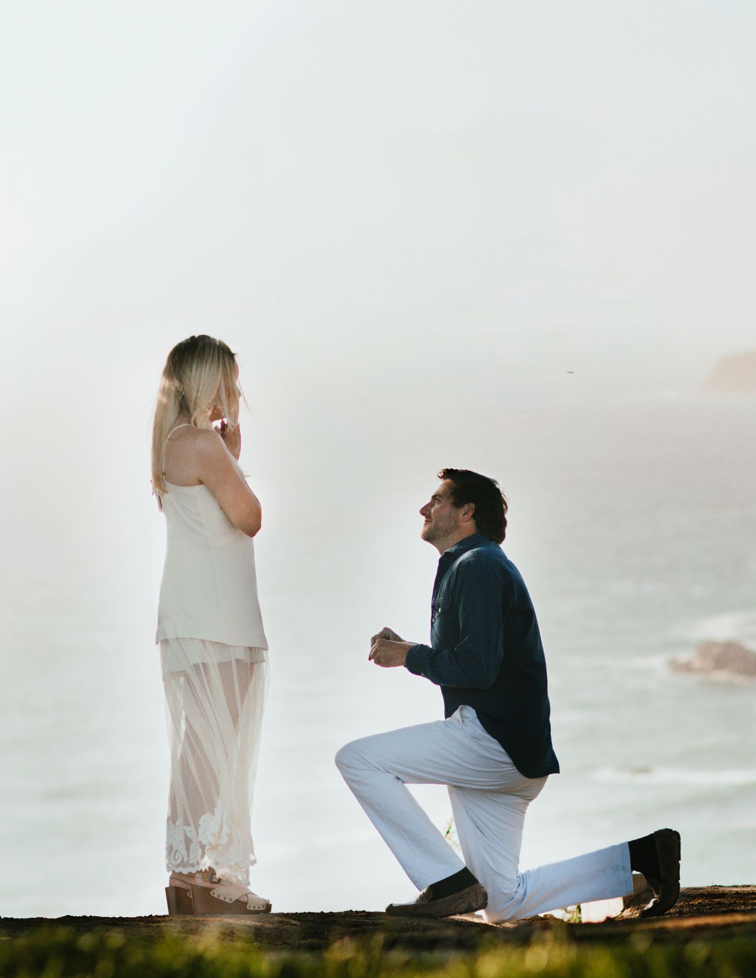 A romantic marriage proposal at sunset with a person kneeling on one knee in silhouette.
