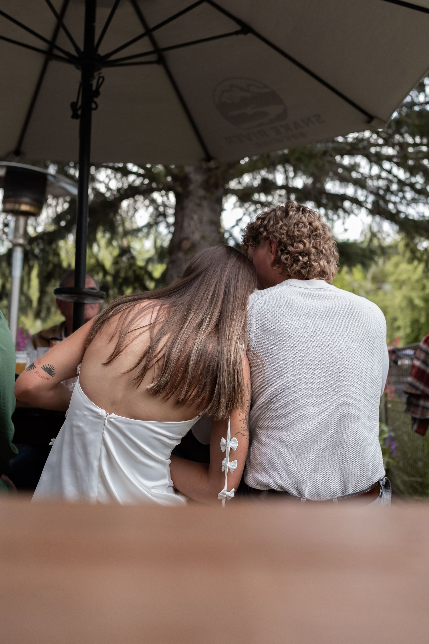 A couple embraces while sitting together on a bench in a park setting.