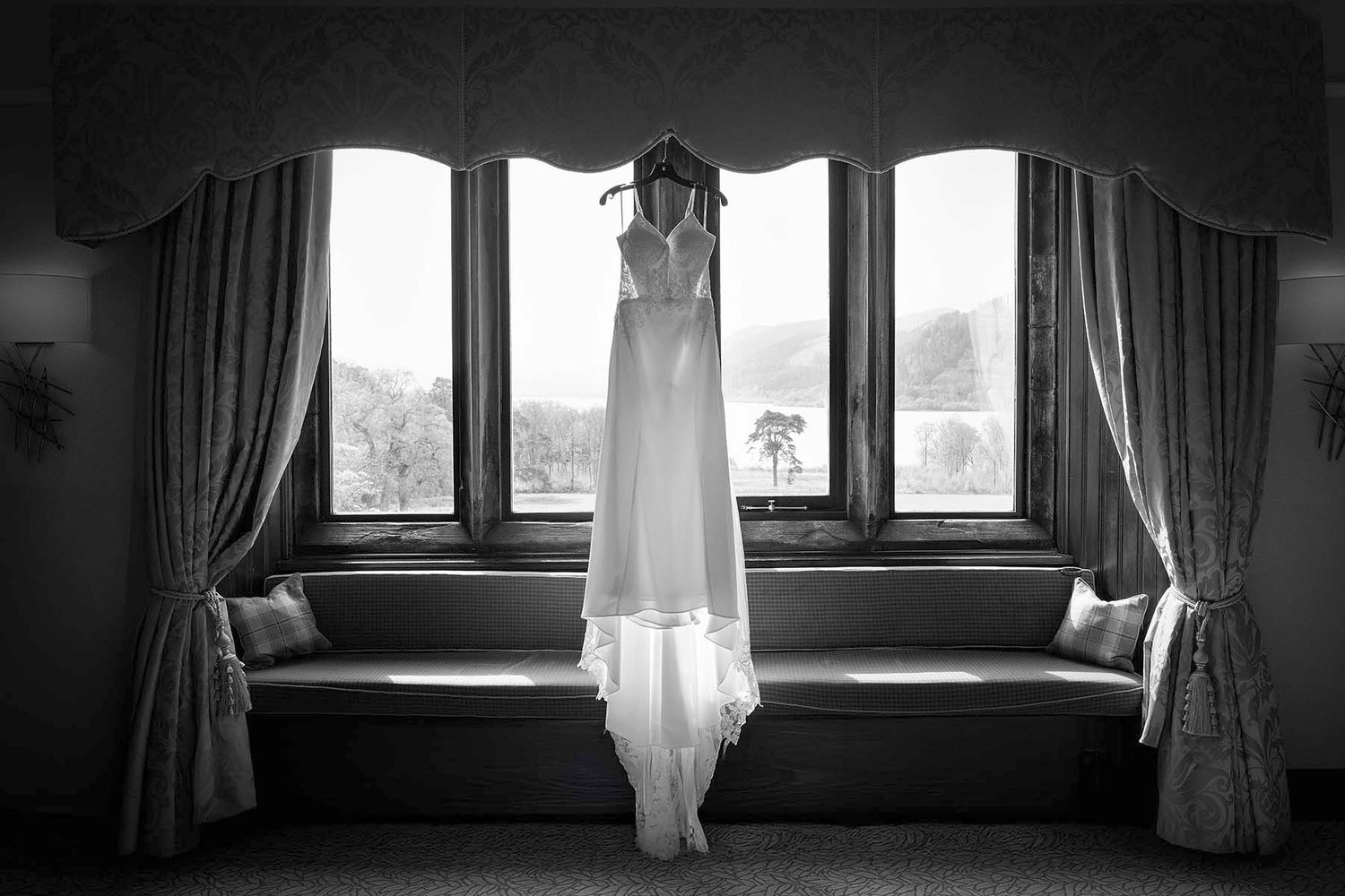 A black and white photo series showing a wedding dress hanging in front of windows with dramatic natural lighting.