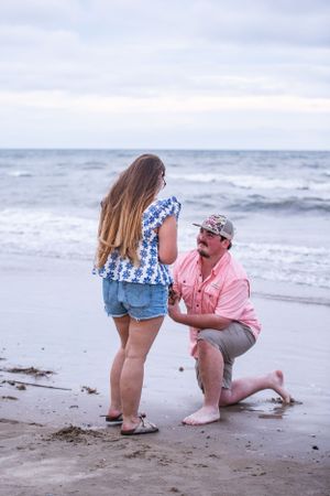 A couple shares a special moment on a beach with rolling waves in the background.