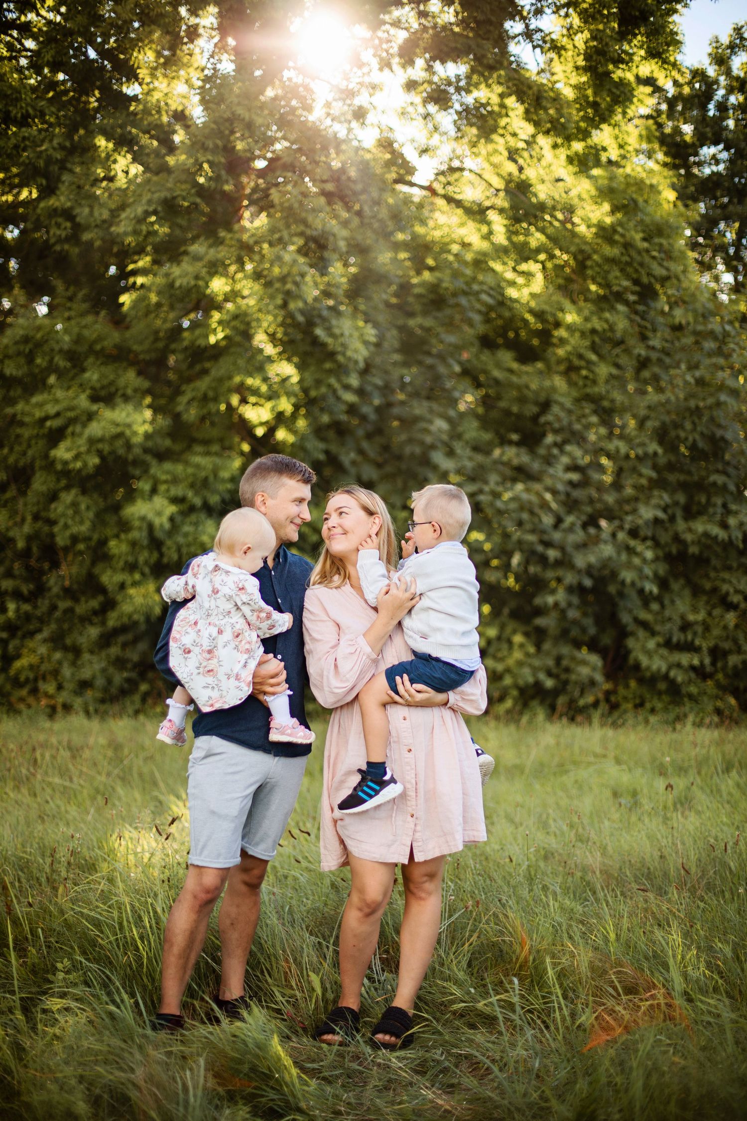 Familjen delar ömma stunder tillsammans på en soldränkt äng under golden hour-fotograferingssessionen.