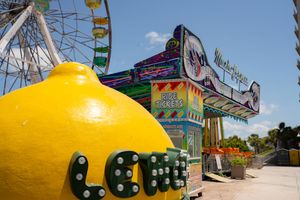 A yellow lemon-shaped robot toy with black wheels and eyes sits on a white surface against a blue sky background.
