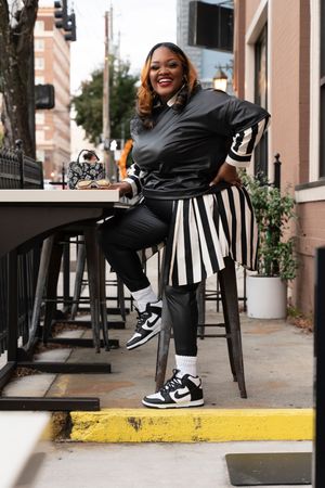 A series of four dynamic shots showing someone in black clothing and sneakers posing on a city sidewalk.