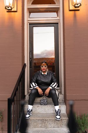 Four identical photos arranged horizontally showing someone sitting on concrete steps wearing black pants and white sneakers.