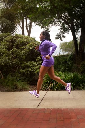 A sequence of athletic movements shows someone jumping and running in purple athletic wear on a brick pathway.