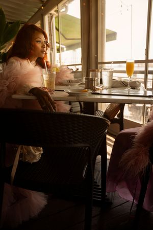 A person sits at a sunlit restaurant table with orange juice and table settings in a modern dining space.