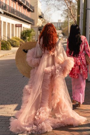 Fashion sequence showing flowing pink tulle dresses and straw hats against an urban backdrop.
