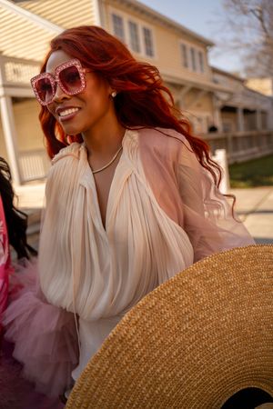 Vintage-inspired fashion shoot with pink dresses and straw hat accessories in golden sunlight.