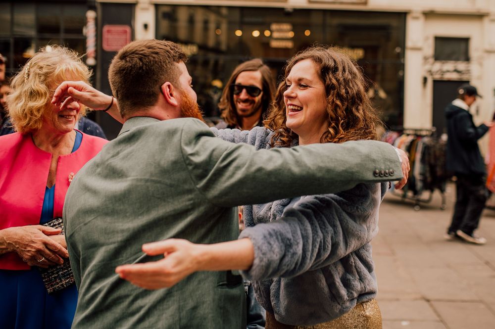 A group of people dancing and celebrating together at an outdoor gathering in an urban setting.