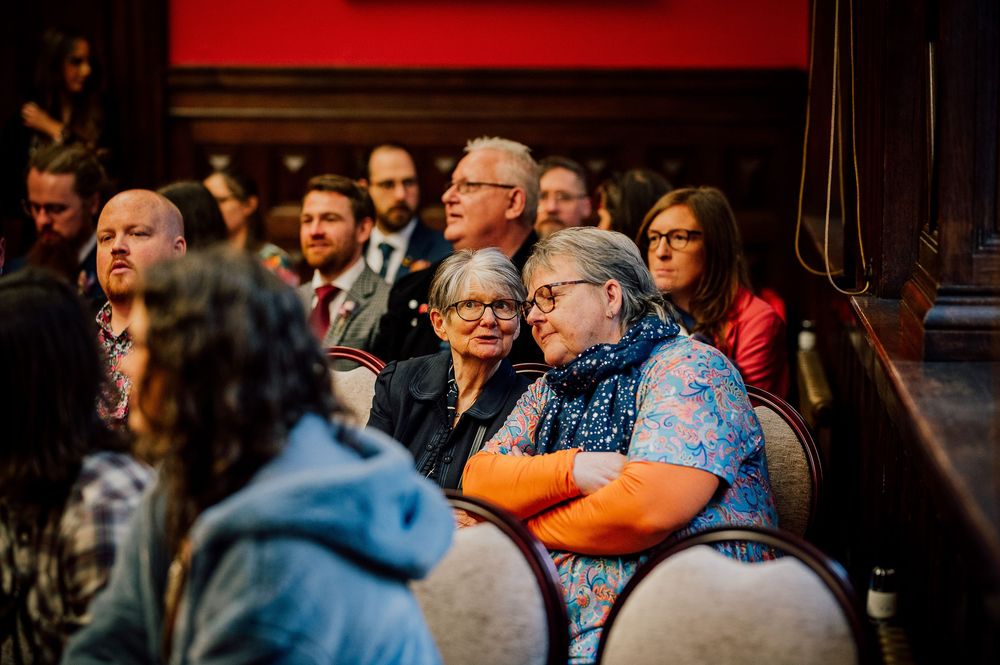 A crowd of attentive audience members watches intently during an indoor event or performance.