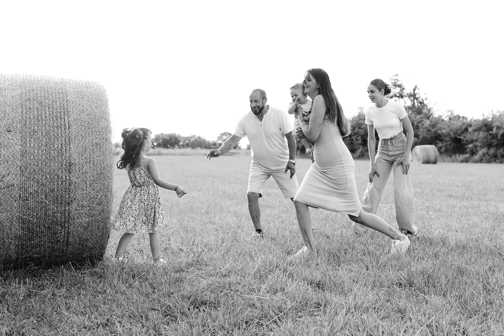 Photo en noir et blanc d'une famille qui joue à 123 soleil dans les champs de blés
