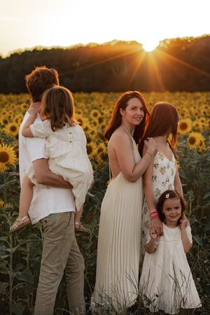 Famille qui pose dans un champ de tournesols au coucher du soleil  pendant la golden hour