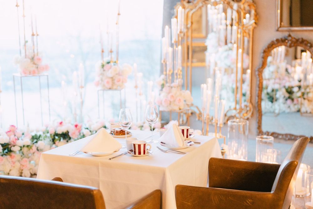 Elegant wedding reception venue with crystal chandeliers and white table settings in a bright, luxurious space.