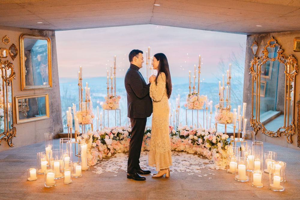 A romantic proposal scene with candles and flowers in an elegant room overlooking a cityscape at dusk.