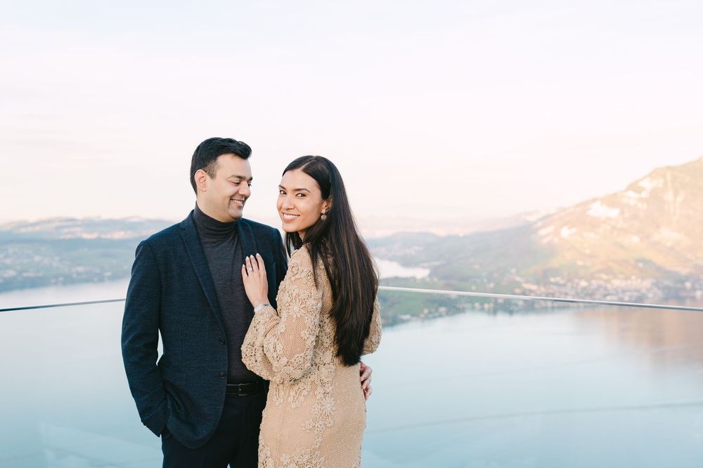 A couple embraces along a scenic mountain lake during sunset creating a romantic silhouette against the water.