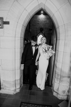 A black and white photo series showing figures walking through stone archways in what appears to be a church hallway.