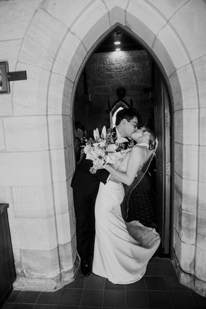 A romantic black and white photo sequence of a couple sharing a tender kiss in a stone archway.