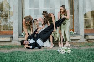 A couple in formal attire shares a romantic moment on a grassy lawn outside a rustic building.