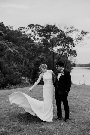 A romantic black and white wedding photo series shows a couple on a grassy hillside with flowing white dress in the wind.