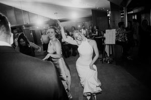 Black and white photo of people dancing energetically at a party or reception on a dance floor.