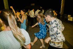 People dancing together at a nighttime party with string lights in the background.