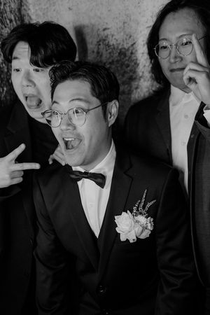 Black and white photo series showing groomsmen making silly faces and gestures at a wedding.