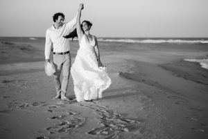 Black and white photographs of people walking along a sandy beach at sunset.