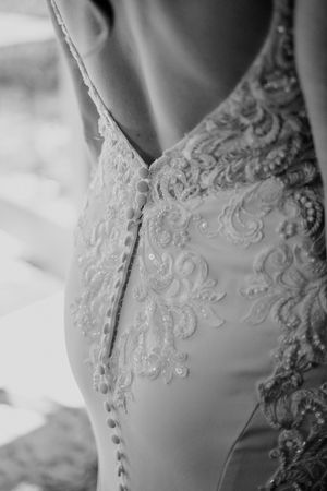Close-up detail of an elegant white wedding dress with intricate lace and beading pattern.