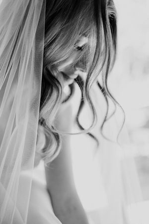 Black and white close-up of a bride wearing a delicate veil with soft curled hair falling gently to the side.