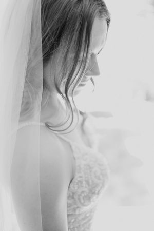 Elegant black and white profile view of a bride wearing a lace wedding dress and delicate veil.